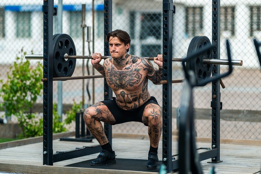 Mand tr�ner udend�rs og laver squat�velse.