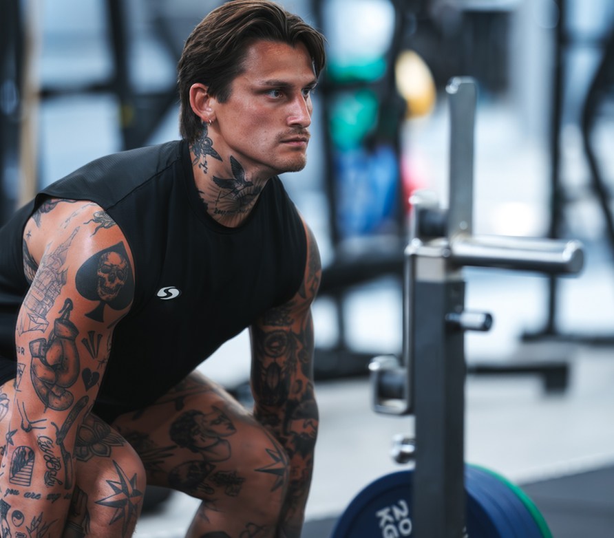 En mand er ved at løfte en stang med vægte på. En mand er ved at løfte en stang med vægte på.